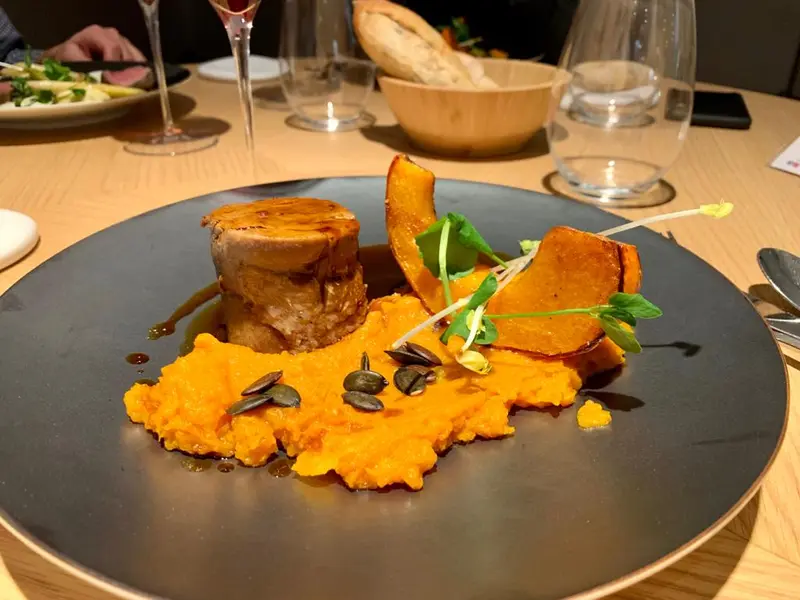 Seared pork medallion on butternut squash purée with roasted squash wedges and pumpkin seeds, fine dining restaurant plate