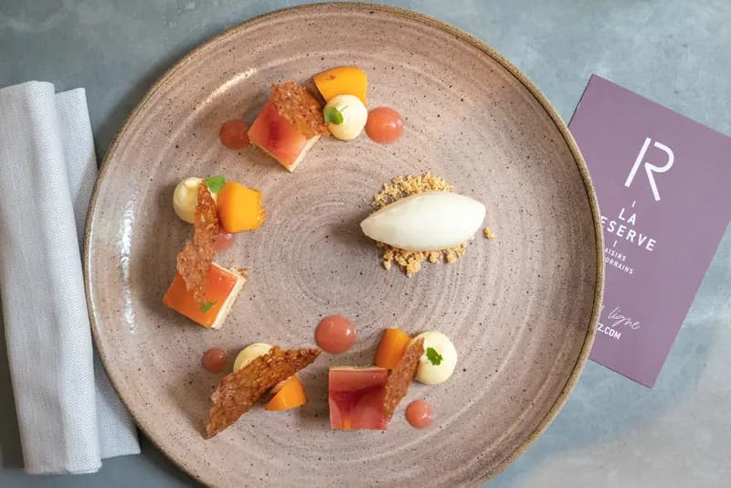 Elegant plated dessert with peach, caramelized tuile, cream dots, and sorbet at La Réserve restaurant, Lorraine.