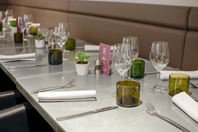Elegantly set dining table at La Réserve restaurant with wine glasses, green glass votive candles, and fresh succulent centerpieces.